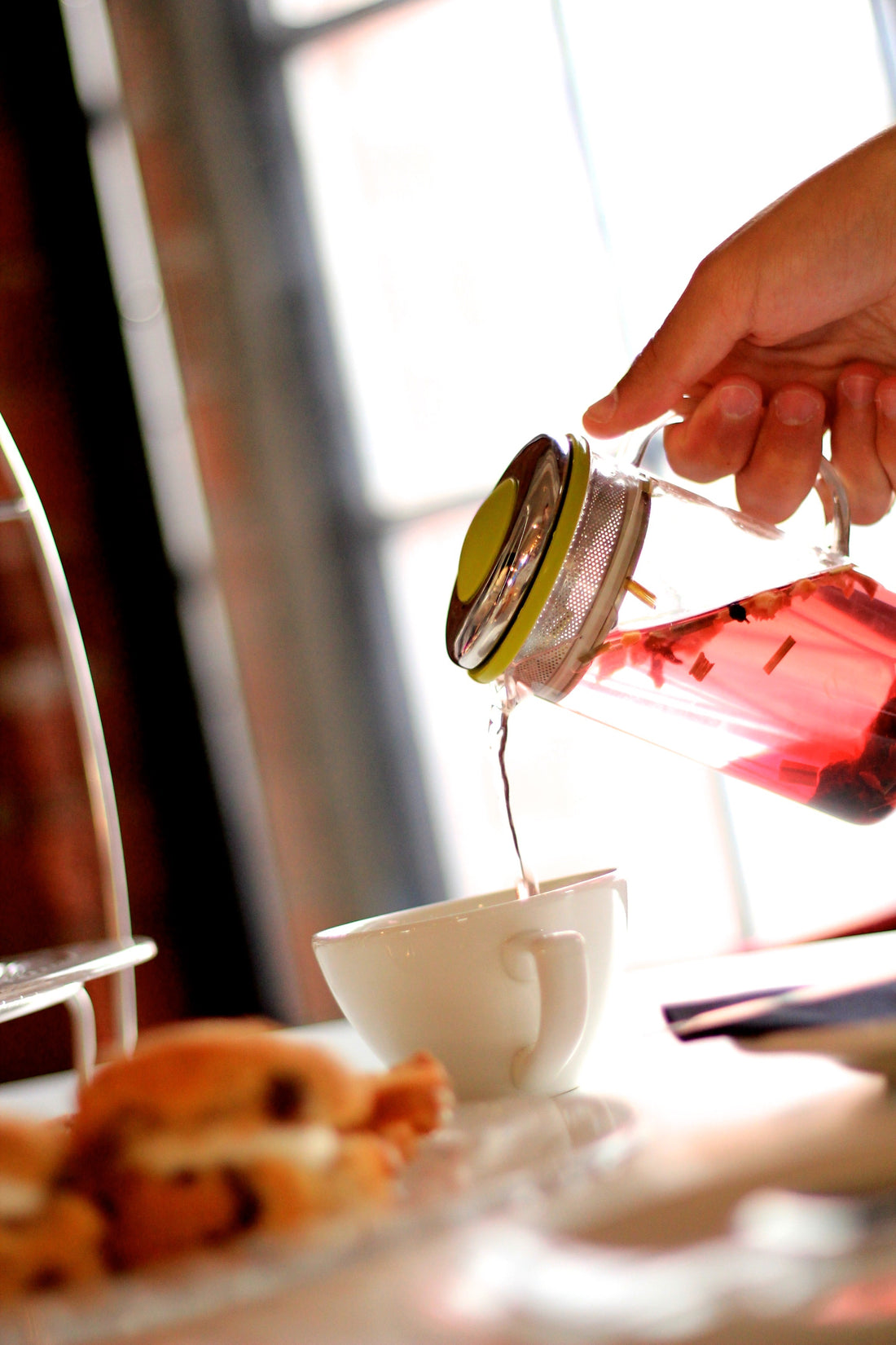 herbal tea being poured from an infuser into a tea cup