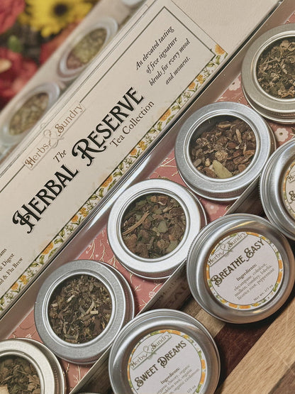 Angled view of The Herbal Reserve box with its printed blend list and row of silver tins