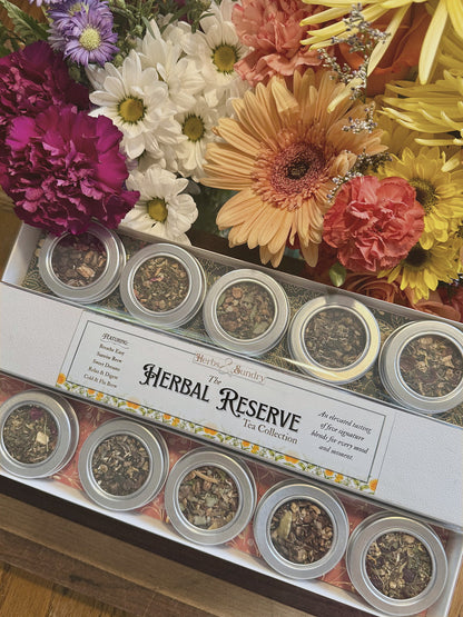 The Herbal Reserve gift box of five silver tea tins, styled with bright gerbera daisies and carnations