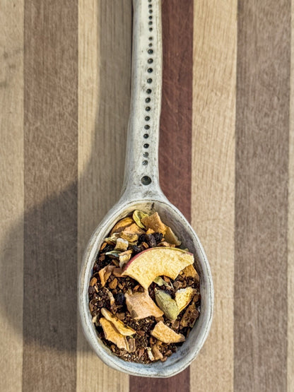 Pale blue spoon holding the Autumn Essence blend of dried apple pieces, cinnamon bark and star anise