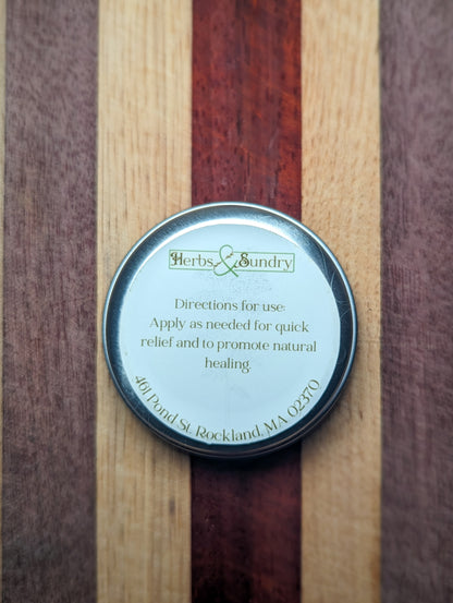 Underside of the Herbal Styptic Powder tin showing the directions label, on a striped wooden board