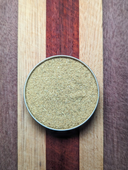Open tin of Herbal Styptic Powder from above, filled with fine pale green yarrow powder